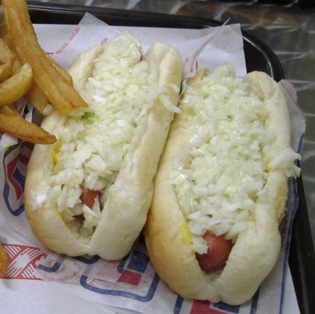 Two steaming Montreal hotdogs, smothered in onions.